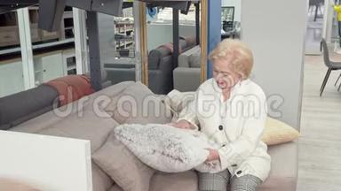 幸福的老年妇女在家具店为自己的客厅挑选靠垫
